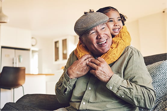 Smiling grandpa in a driver's cap, hugging his granddaughter at his West Fargo home in North Dakota