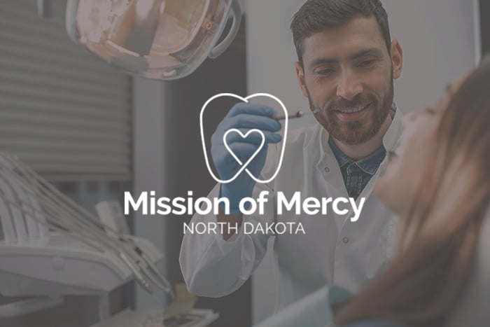 Mission of Mercy North Dakota logo with a friendly dentist helping a patient in Bismarck, ND