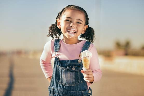 Young girl laughing while eating ice cream, posing for a photo on Main Street in Carrington, ND